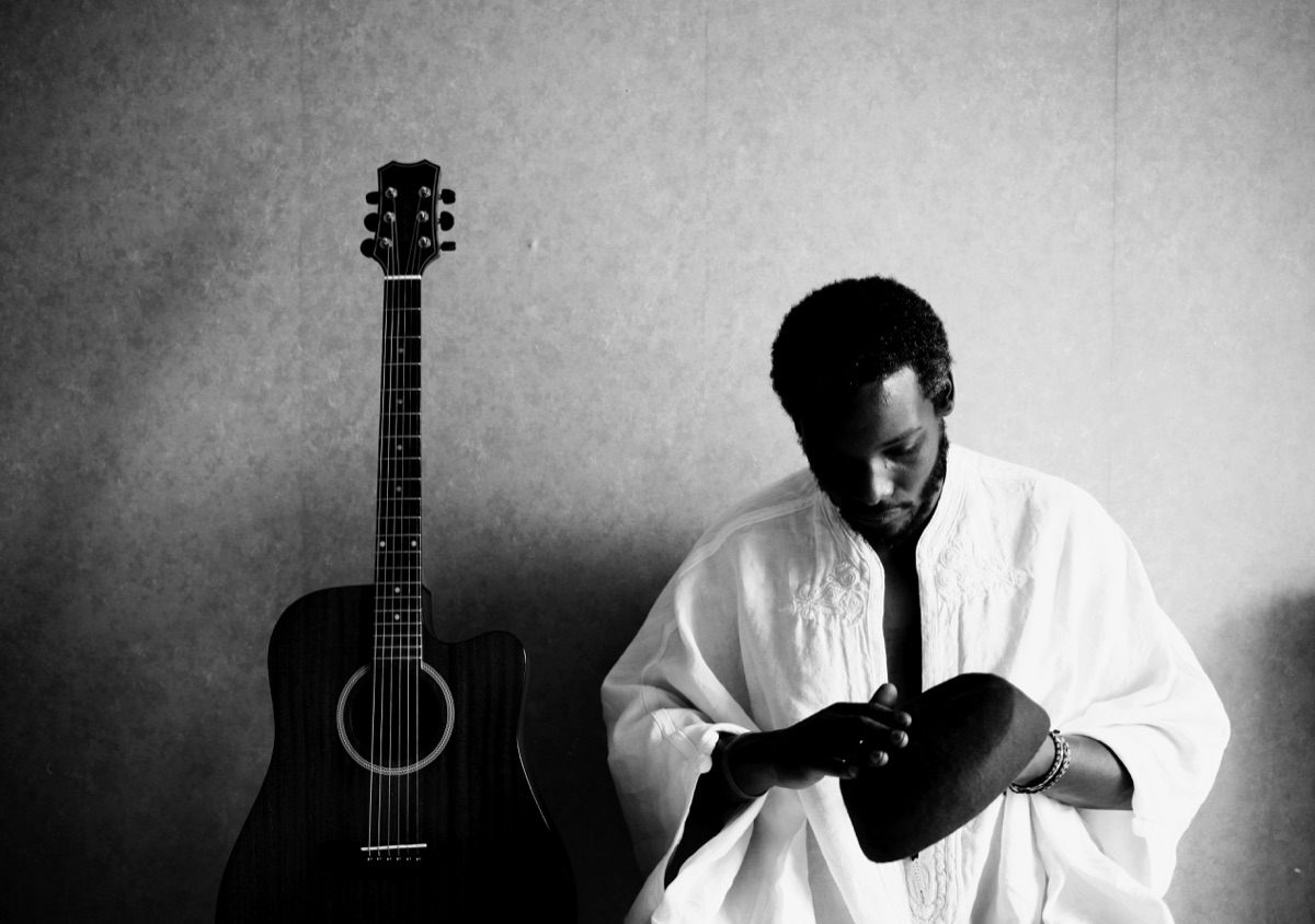 Sabry Mosbah en djellaba blanche, guitare à ses côtés